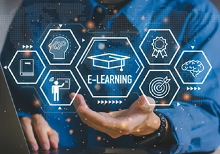 Person using a laptop with digital e-learning icons, including a graduation cap, certificate, instructor, brain, and target, displayed above an outstretched hand with the text “E-Learning.”