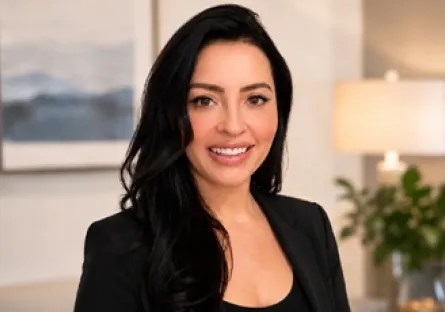 **Alt text:** Portrait of Kelly Sukkha smiling and wearing a black blazer in a professional indoor setting.
