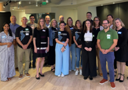 **Alt text:** Group of faculty and staff stand together smiling during a professional gathering.