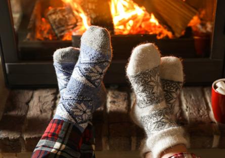 two pairs of feet wearing wooly socks in front of fire with hot cocoa